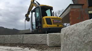 Bagger hebt Mauerblock